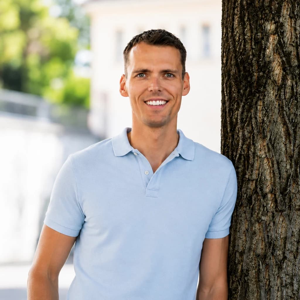 Lukas Jud steht lächelnd neben einem Baum.